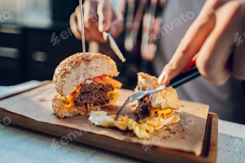 Preview: Bearded man sitting in a restaurant and eating a fresh tasty burger