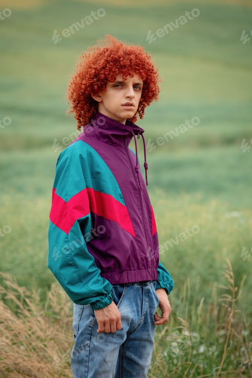 Preview: young guy with red curly hair in 80s sports suit on the field