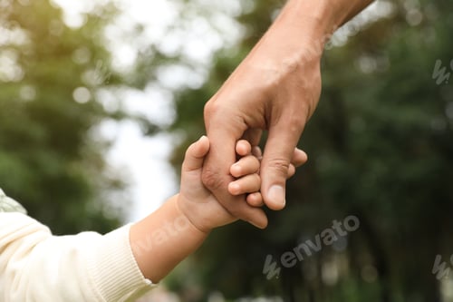 Preview: Daughter holding father's hand in park, closeup. Happy family