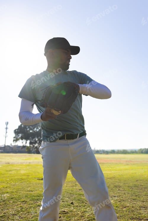 Preview: Adult male baseball player standing on grassy field wearing cap, holding glove, preparing to throw