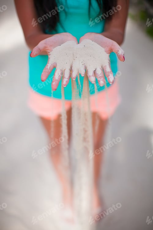 Preview: White sand through the fingers of the young girl