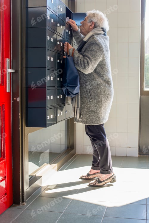 Preview: Elderly person checking mail at a wall of postboxes