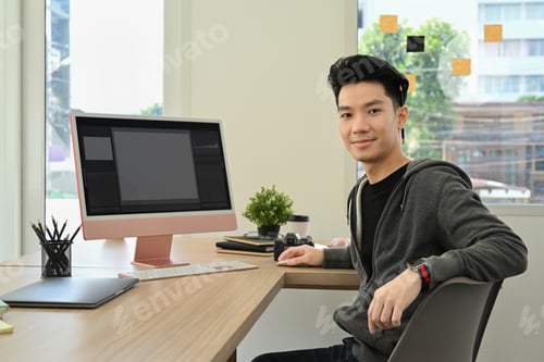 Preview: Handsome male photo editors sitting in creative workplace front of personal computer.