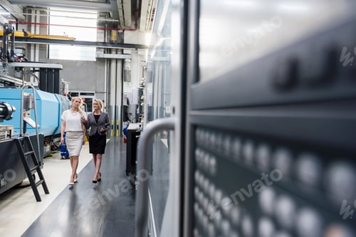 Preview: Two women with tablet walking and talking in factory shop floor