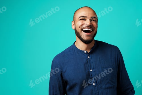 Preview: Joyful dark-skinned man laughing against turquoise background