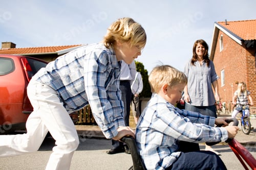 Preview: Side view of boy pushing brother on quadricycle