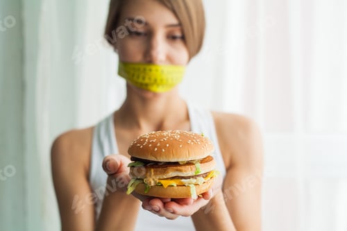 Preview: Young woman with duct tape over her mouth, preventing her to eat junk food