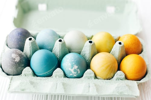 Preview: Stylish Easter eggs in carton tray on white wooden background