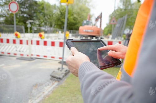 Preview: Close up of foremans hands using digital tablet on road construction site