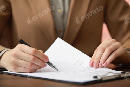 Preview: Woman signing documents at wooden table in office, closeup