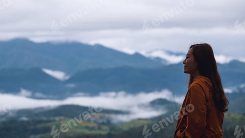 Preview: Portrait image of a female traveler looking at a beautiful foggy mountain and nature view