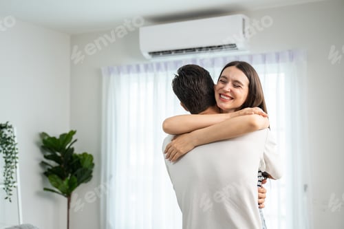 Preview: Caucasian young man and woman hugging each other in living room at home.