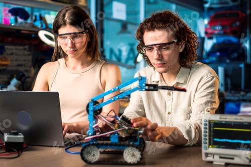 Preview: Young man and woman doing experiments in robotics in a laboratory