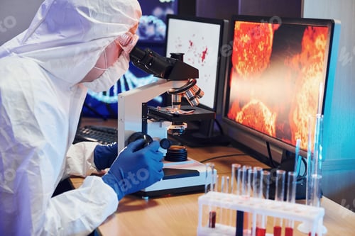 Preview: Scientist in white protective uniform near displays with data works with coronavirus and blood tubes