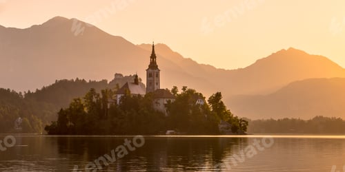 Preview: Island with church in lake Bled on orange hazy morning