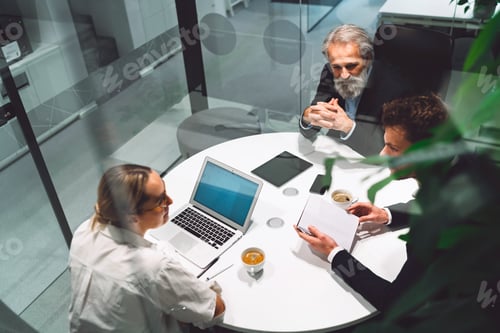 Preview: Top down view of three business people sitting by the round table, having a business meeting in a