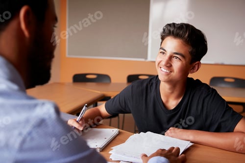 Preview: High School Tutor Giving Male Student One To One Tuition At Desk