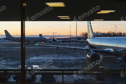 Preview: The view from the window on a parked passenger plane at sunset.