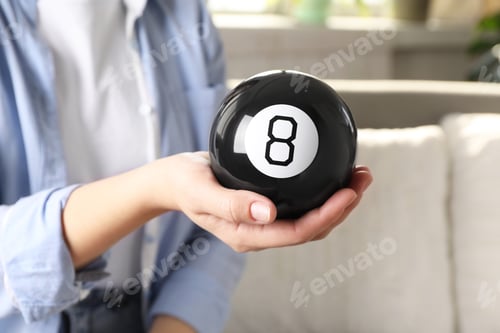 Preview: Woman holding magic eight ball indoors, closeup