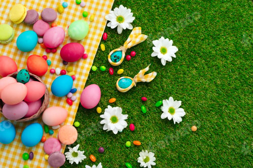 Preview: Colored eggs and vibrant candies on grass. Easter composition
