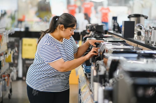 Preview: Smart modern female customer choosing coffee machine at electronics store