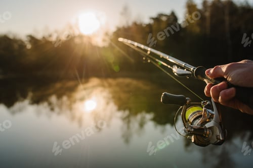 Preview: Fisherman with rod, spinning reel on the river bank. Sunrise. Fishing for pike, perch, carp. Fog