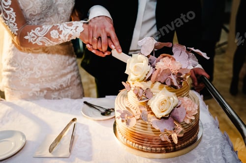 Preview: Bride and a groom is cutting their rustic wedding cake on wedding banquet. Hands cut the