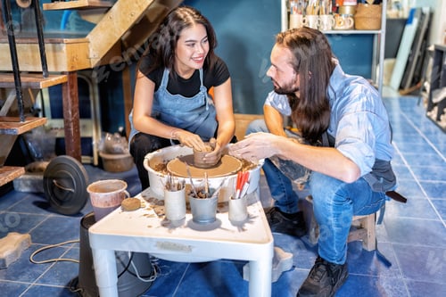Preview: Man potter teaching pot making women learn on potters wheel making clay objects in pottery workshop
