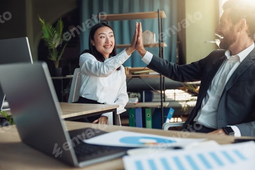 Preview: Two happy business colleagues clap hands after finishing work on project