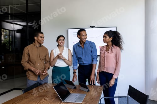 Preview: Diverse business team discussing project in modern office with laptops on table