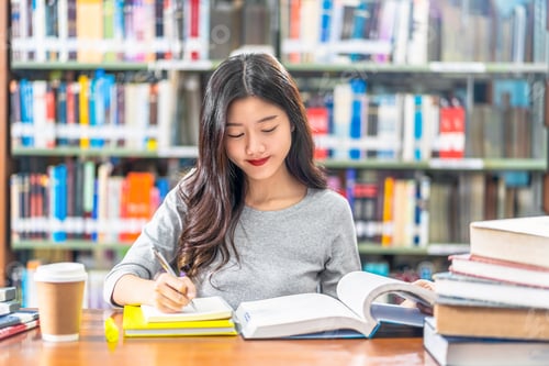 Preview: Asian young Student in casual suit reading and doing homework in library of university or colleage