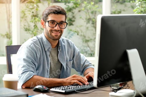 Preview: Handsome engineer man is typing computer on the table in the office with glass window.