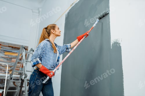 Preview: Female house painter in gloves paints the wall