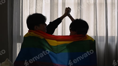 Preview: Silhouette of same sex couple sitting under rainbow flag. LGBT, pride, relationships and equality.