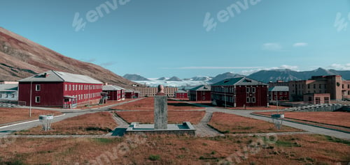 Preview: Abandoned buildings in Pyramiden Svalbard under bright blue sky with distant mountains