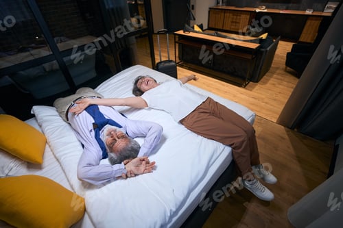 Preview: Tired from road, but happy elderly spouses are resting on bed