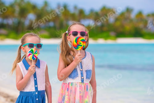 Preview: Two little girls eating bright lollipops on the beach