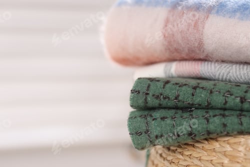 Preview: Wool scarves on wicker box against light background, closeup. Space for text