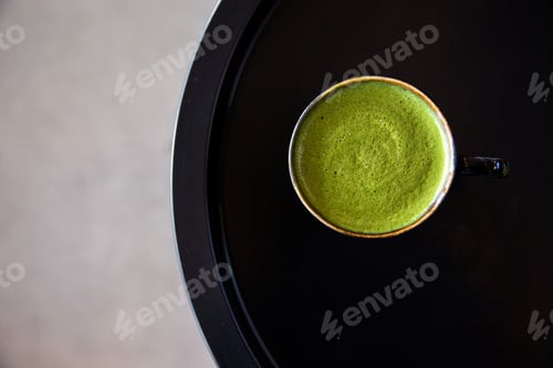Preview: Tasty matcha drink in black cup on black table background.