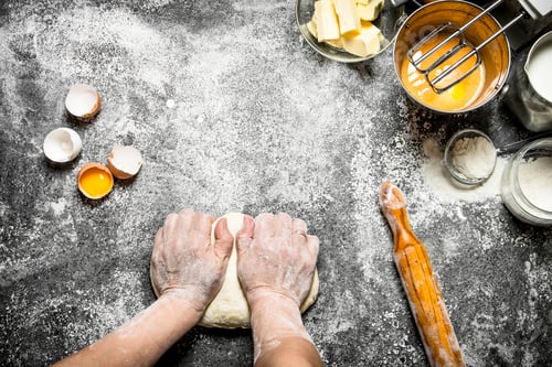 Preview: Dough background. Woman kneads dough with various ingredients on the table.
