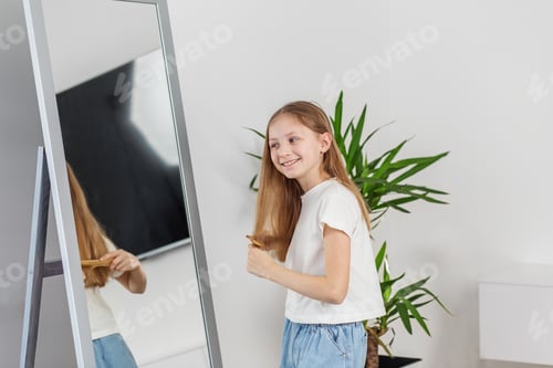 Preview: Young Girl Brushing Hair in Mirror. Morning preparation before school.