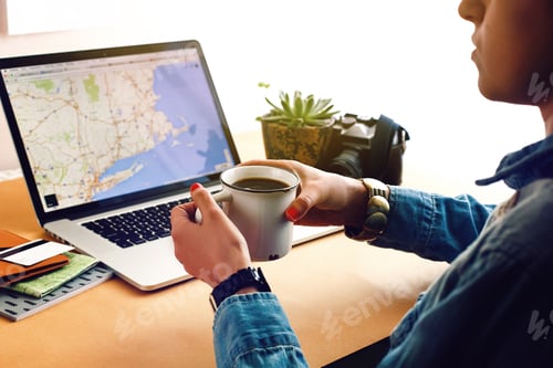 Preview: stylish girl holding coffee on background of laptop map card and succulent