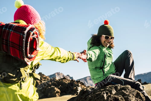 Preview: Couple of happy woman helping eachother to arrive to the top of the mountain - enjoy