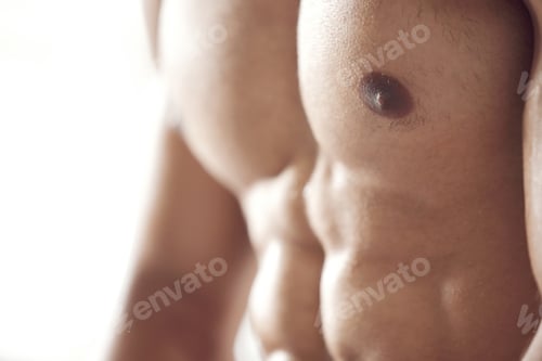 Preview: Closeup of one fit topless mixed race man with muscular hard six pack abs from regular exercise in