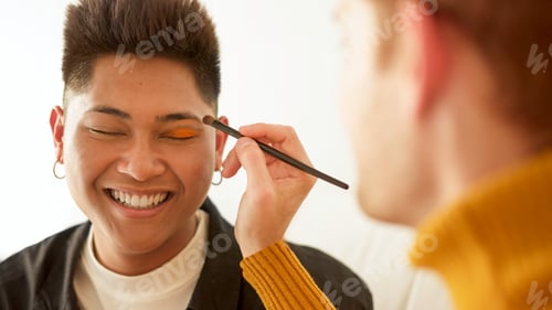 Preview: Gay man applying make up to her partner while smiling