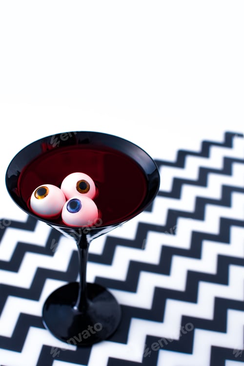 Preview: Halloween cocktail decorated with eyeballs in black martini glass.