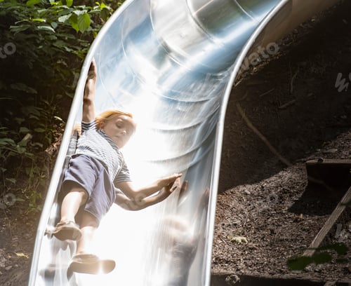 Preview: Boy sliding down playground slide