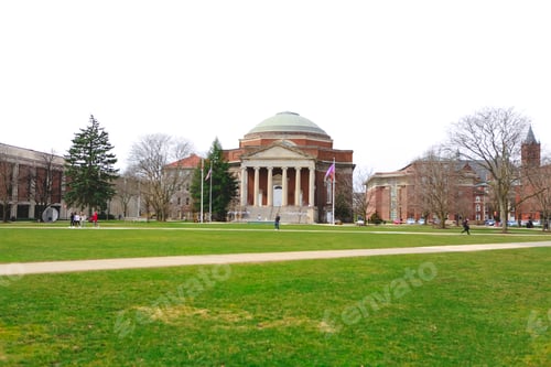 Preview: Syracuse University campus, grassy green quad with students walking in the distance