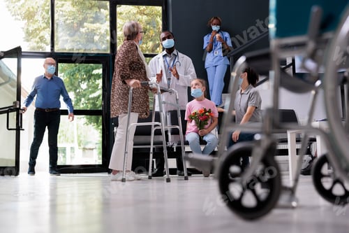 Preview: Elderly patient with walking frame discussing health care treatment with medic in hopsital waiting