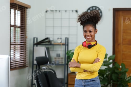 Preview: Happy african american young woman standing looking at camera posing at home office arms crossed.